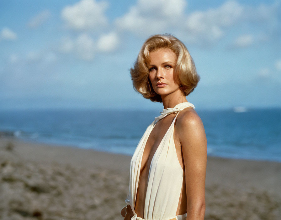 Blonde woman on beach gazes at ocean