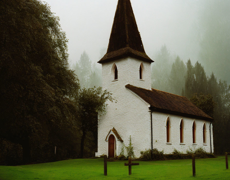 White church with pointed steeple in misty forest landscape