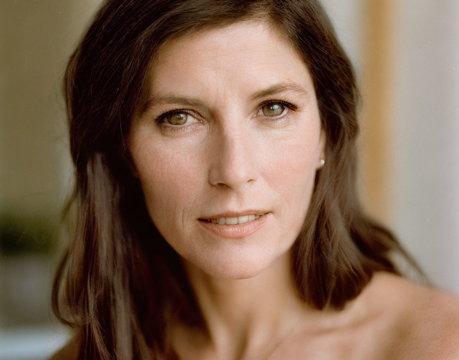 Portrait of woman with long dark hair and faint smile, close-up shot.