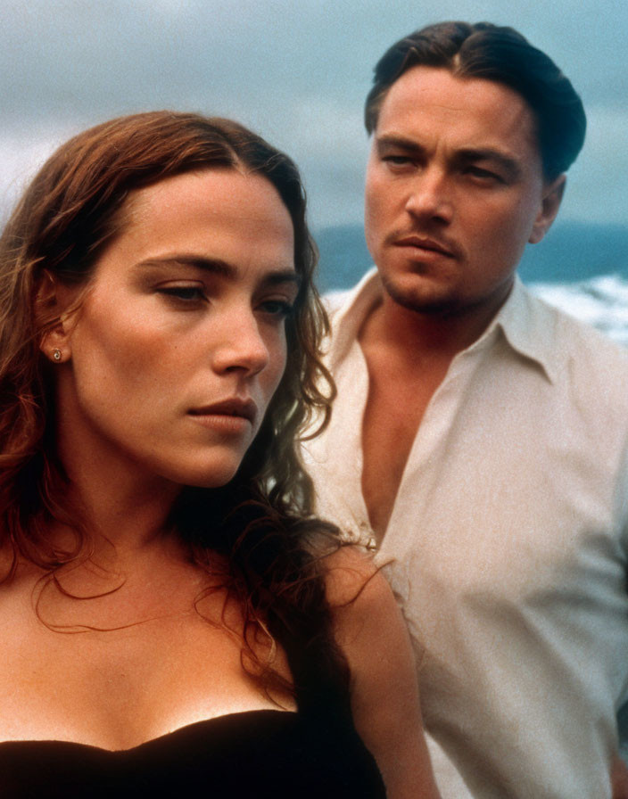 Woman in black and man in white standing together with seascape background.