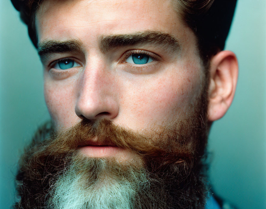 Portrait of Young Man with Full Beard and Blue Eyes in Dark Cap