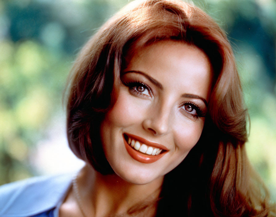 Smiling woman with long wavy hair in blue top.