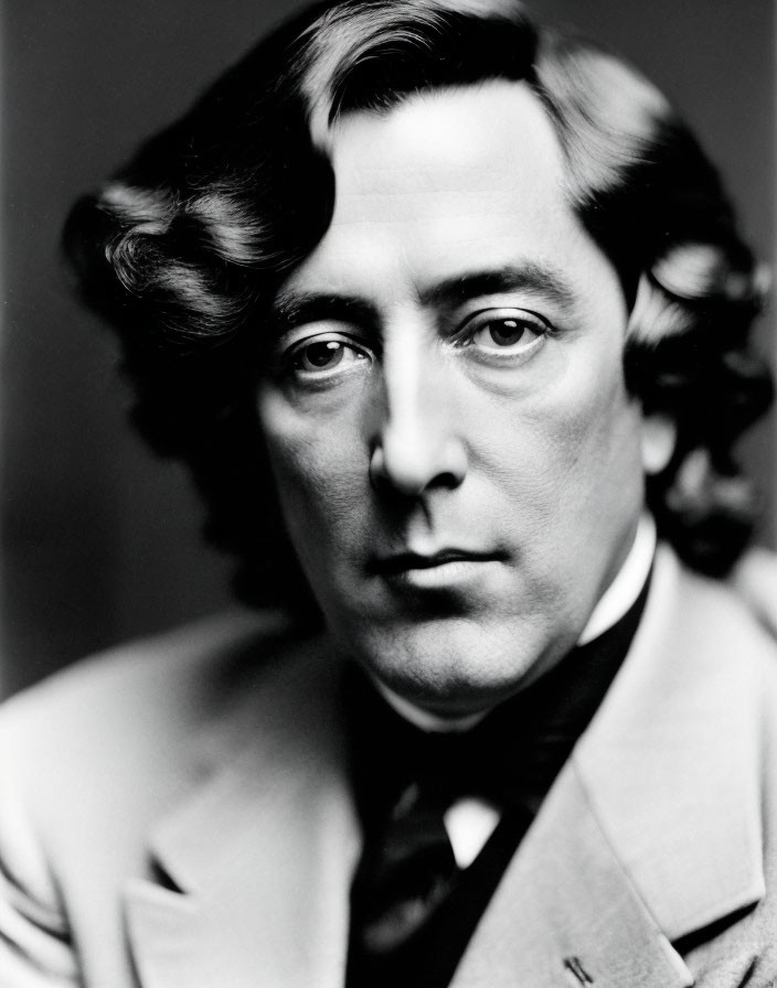 Monochrome portrait: man in suit with wavy hair, intense gaze