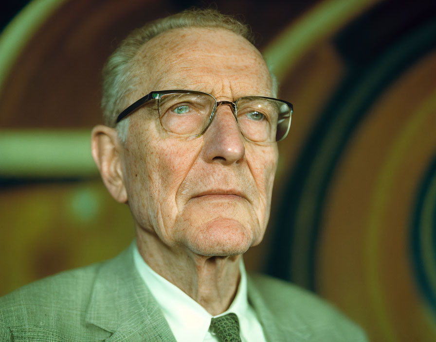 Elderly man in glasses against colorful abstract backdrop