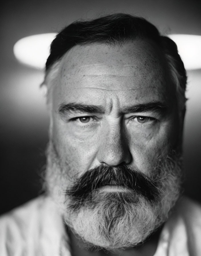 Monochrome portrait of bearded man with intense gaze and halo light