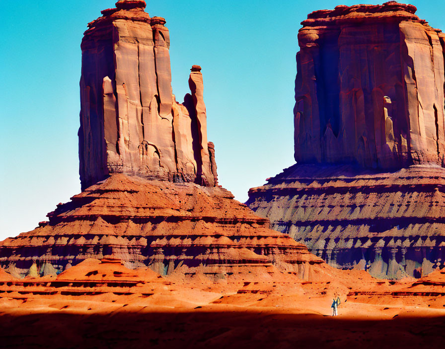 Person between towering red sandstone buttes in Monument Valley