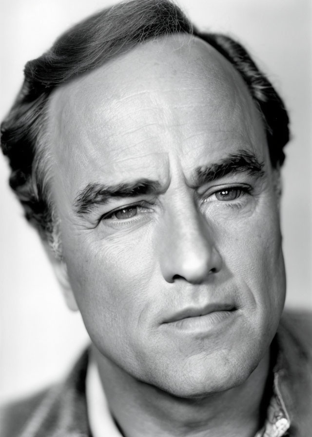 Monochrome headshot of middle-aged man with intense gaze and dark hair