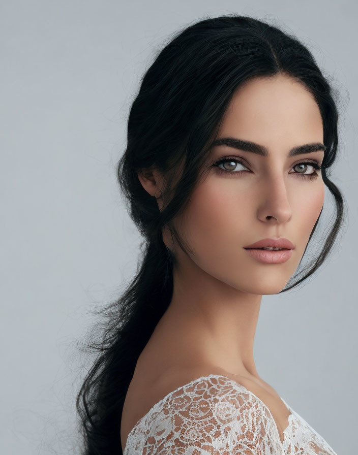 Portrait of woman with dark hair and striking eyes in white lace top