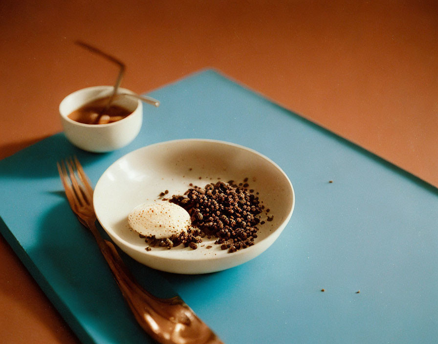 Poached egg and black beans bowl on blue placemat with wooden utensils