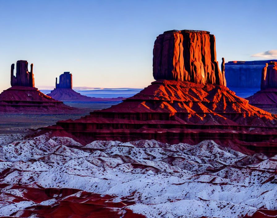 Iconic Monument Valley rock formations in warm sunset glow with vibrant colors and contrasting shadows