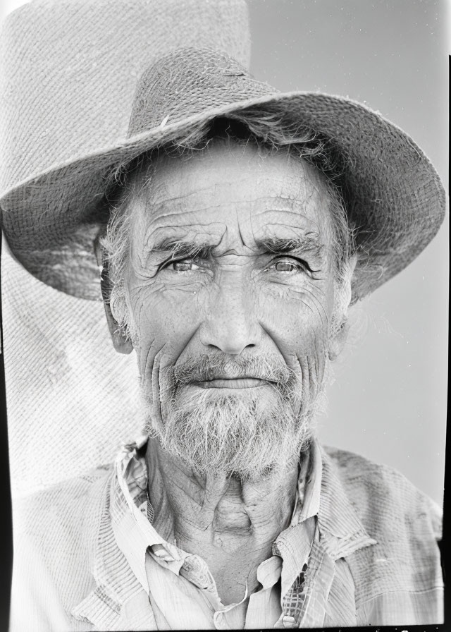 Elderly man with weathered face and wide-brimmed hat gazes calmly.