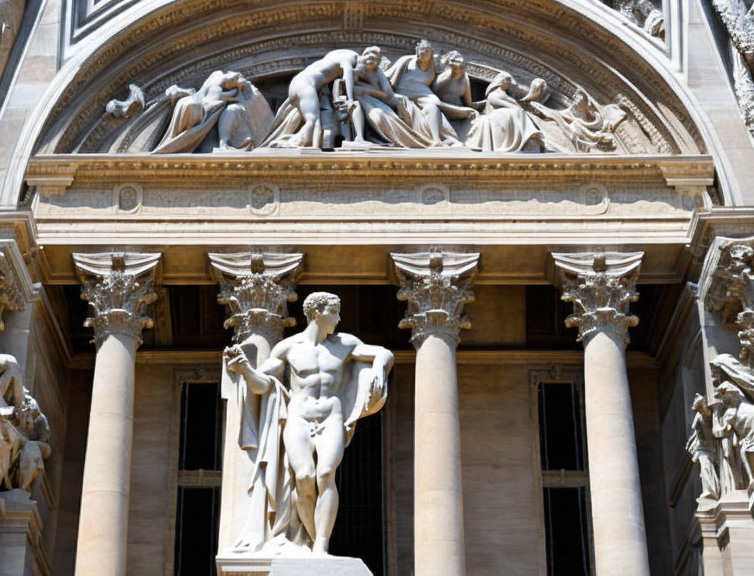 Marble statue of muscular male figure with intricate stone sculpture on building pediment