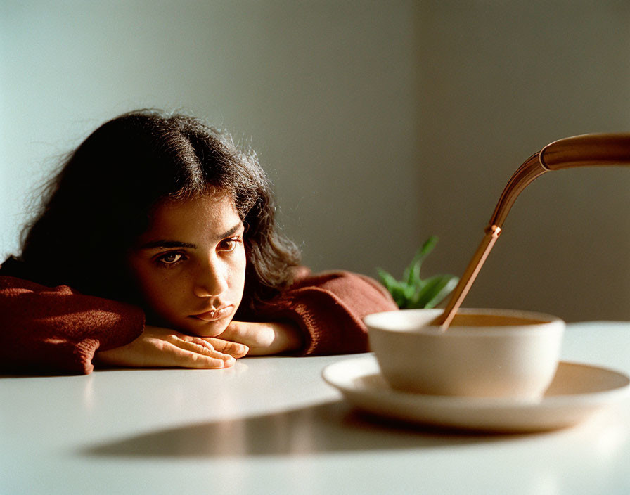 Woman Contemplating Coffee at Table in Natural Light