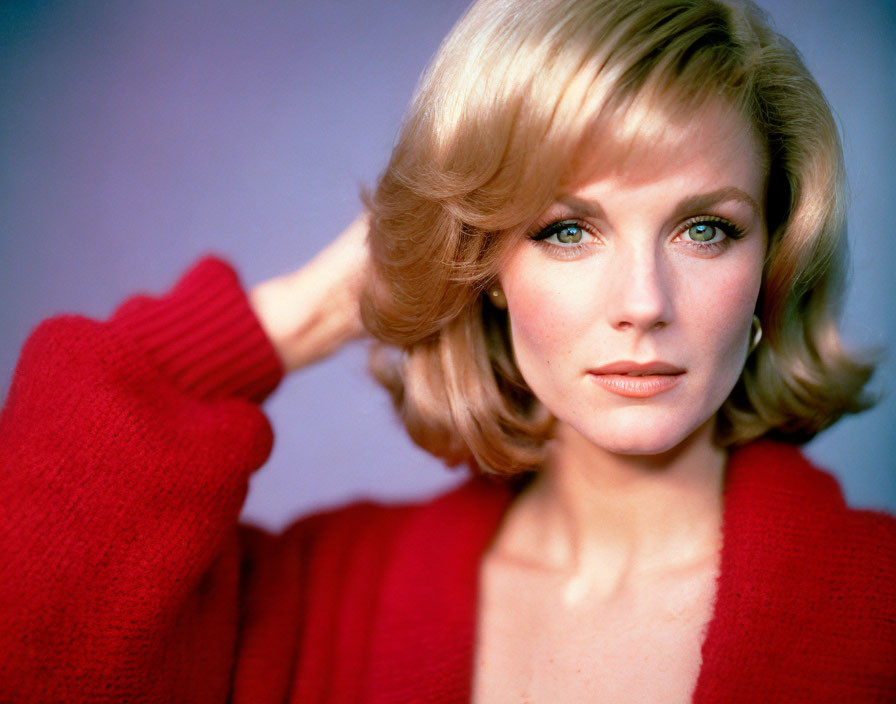 Blonde woman in red sweater with hand on head