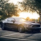 Blue Sports Car with White and Orange Stripes on Empty Road at Sunrise