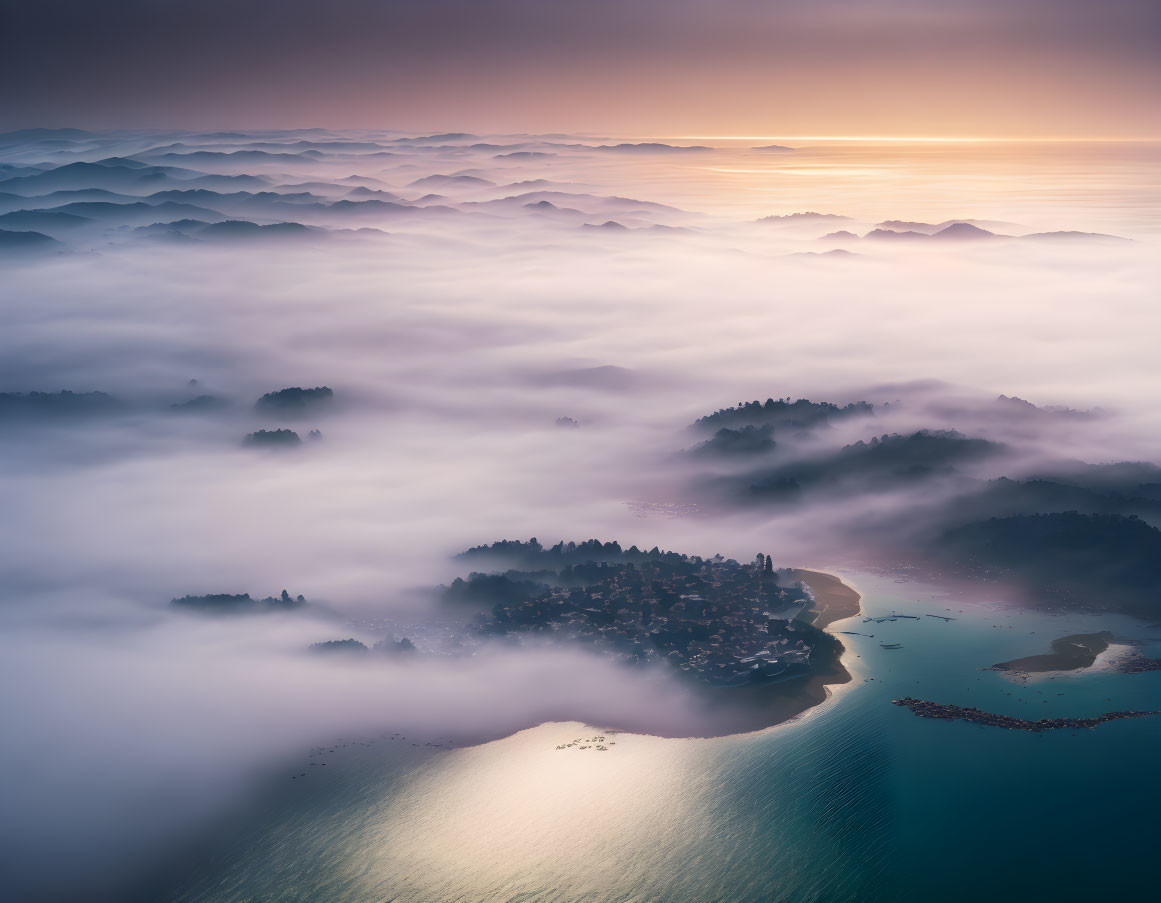 Misty mountains, village, and tranquil shoreline at sunrise