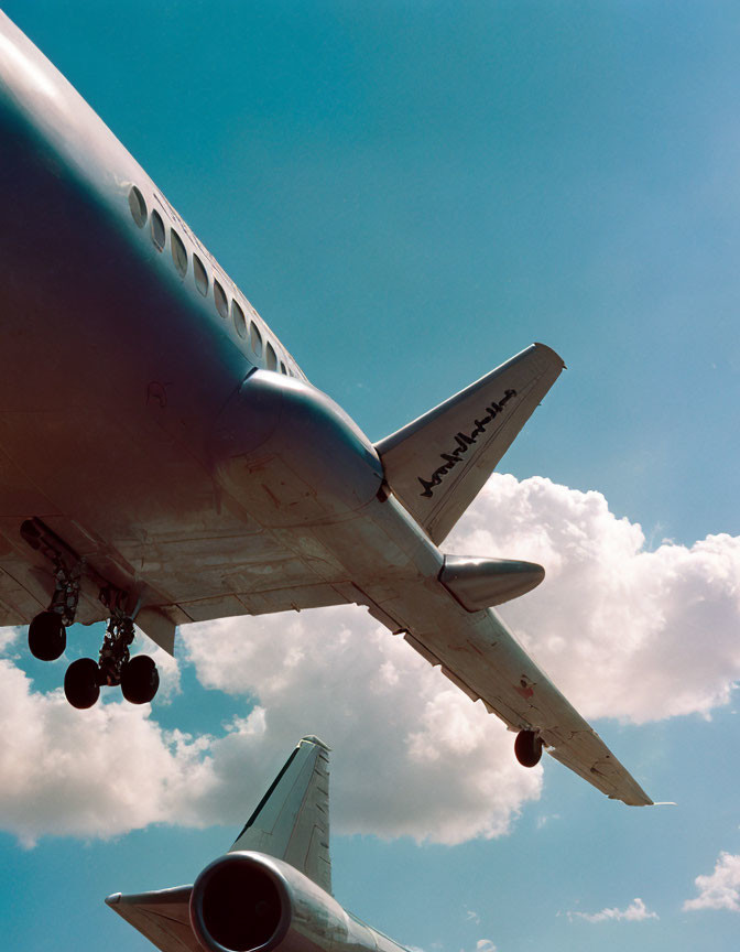 Low angle view of airplane with extended landing gear against blue sky.