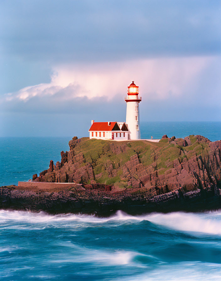 Scenic red-and-white lighthouse on rocky cliffs by blue ocean