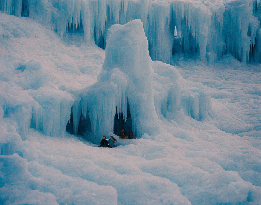 People sitting in frozen landscape with towering ice formations.