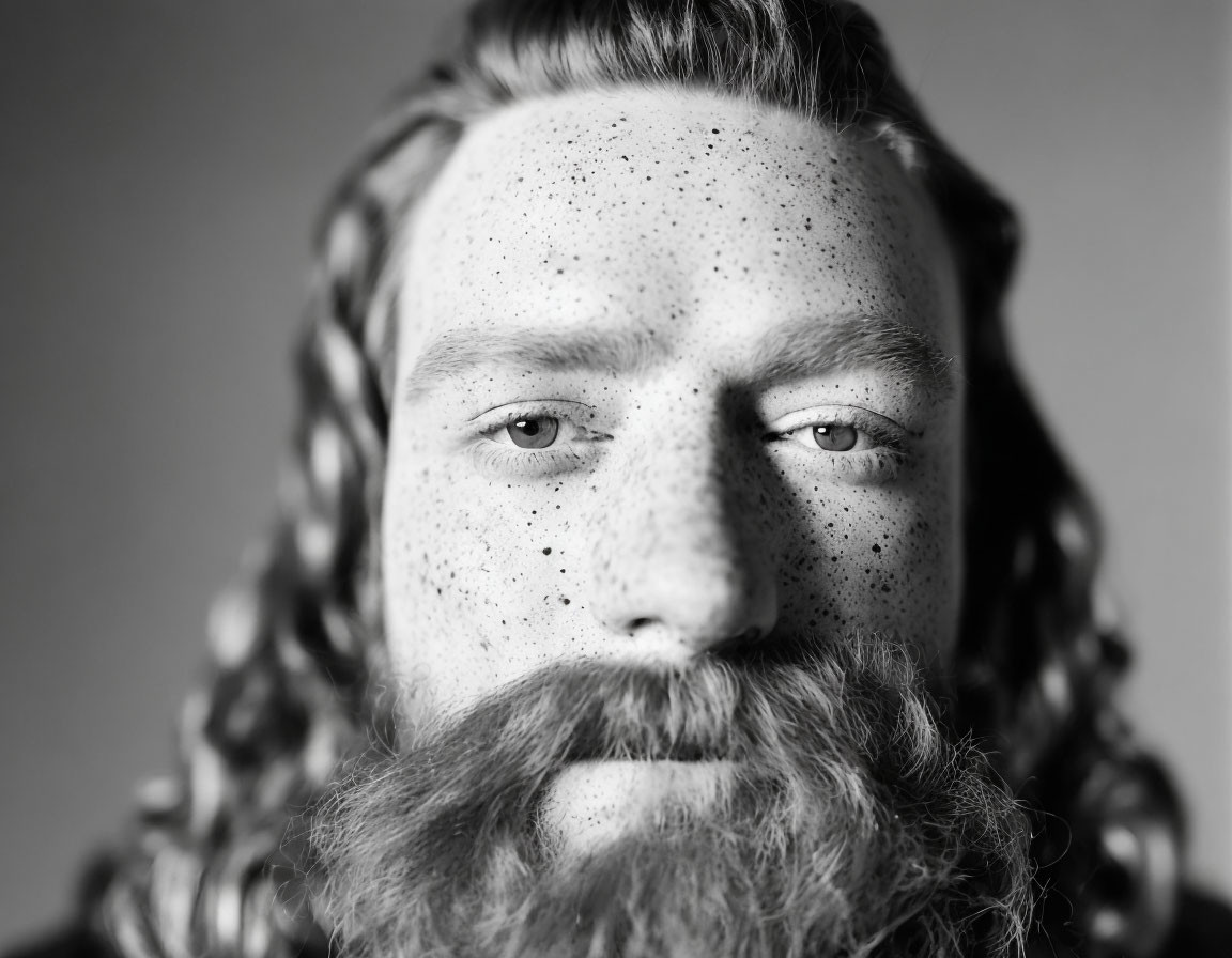 Monochrome portrait of a man with full beard and freckles