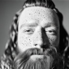 Monochrome portrait of a man with full beard and freckles