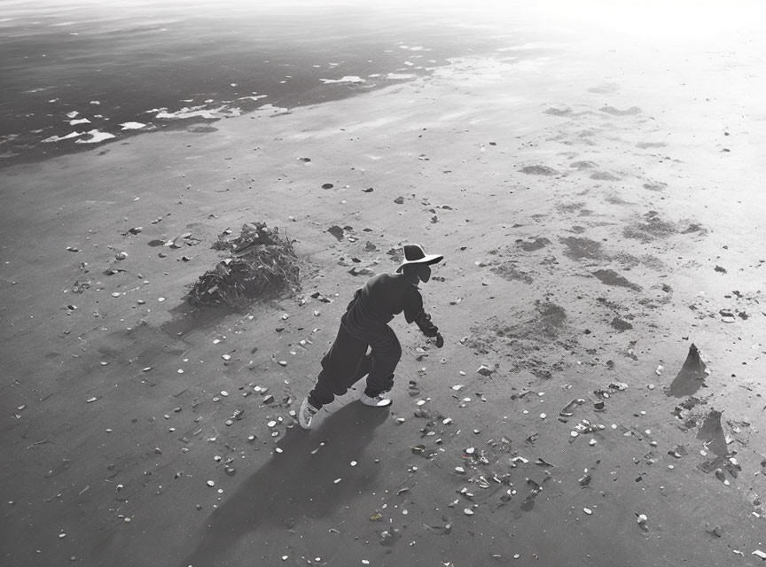 Cowboy hat person running on sandy beach with footprints.