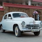 Vintage White Car Parked in Front of Old Building with Rustic Facade