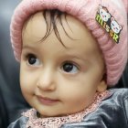 Child in Pink Knitted Hat and Navy Blue Coat with Buttons