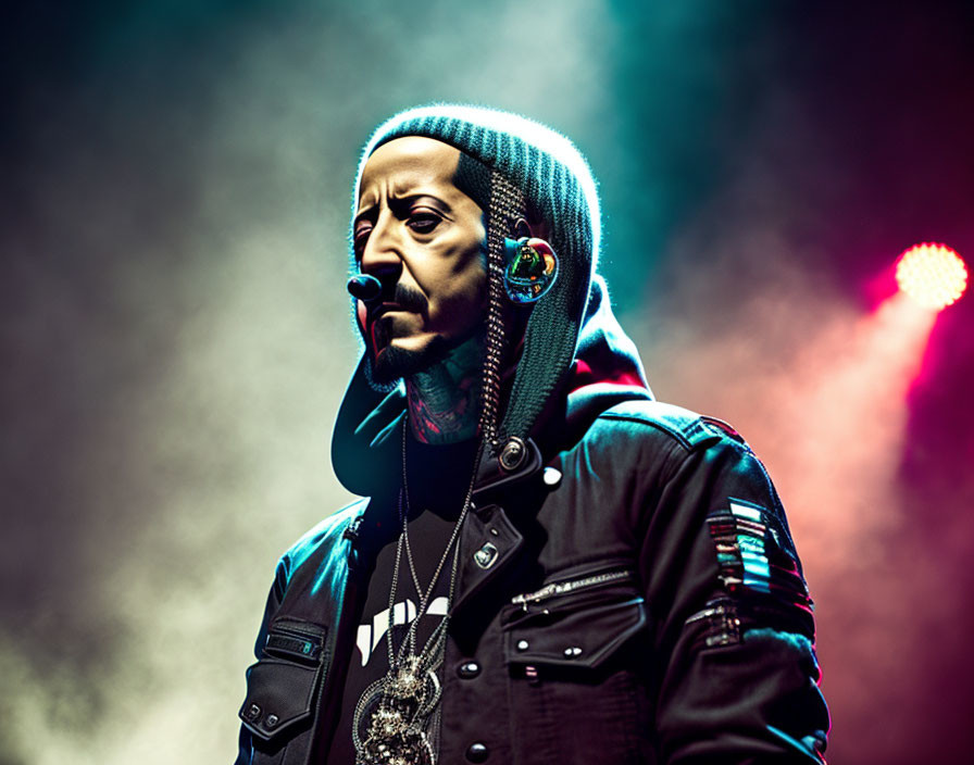 Man on Stage in Beanie and Jacket with Serious Expression under Colorful Lighting