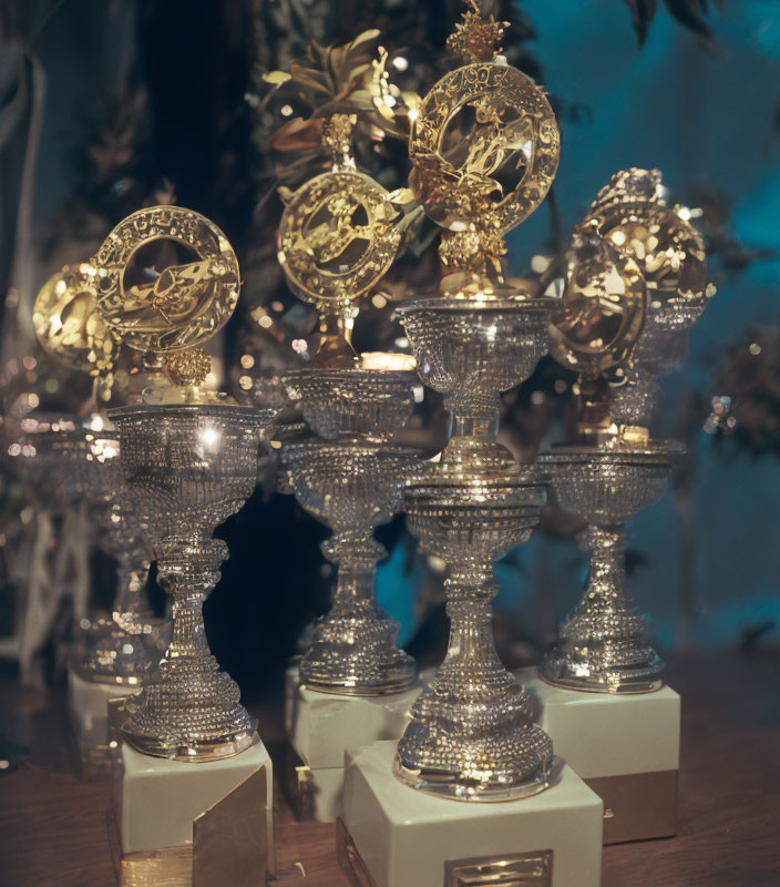 Intricate Golden Trophies on Pedestals Reflecting on Glossy Surface