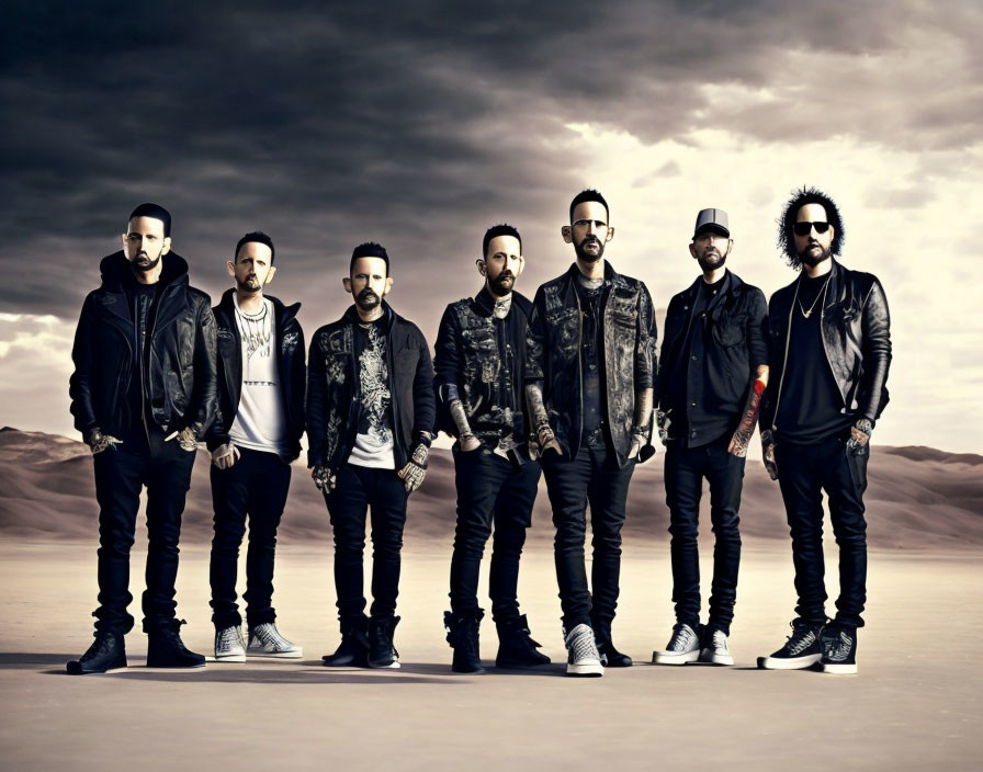 Seven men in stylish casual clothes in desert setting under dramatic cloudy sky