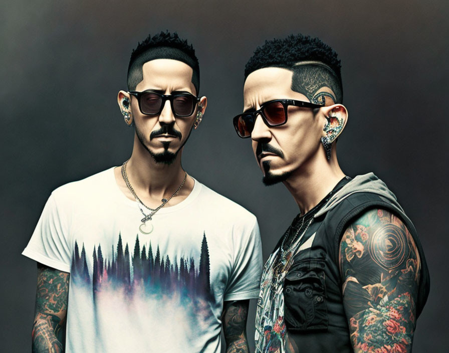 Two tattooed men in sunglasses, one in white tee, one in black tank top, against muted