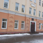 Group of people engaging in activities outside worn-down peach-colored building