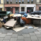 Group of People with Backpacks Gathered Around Cardboard in Parking Lot