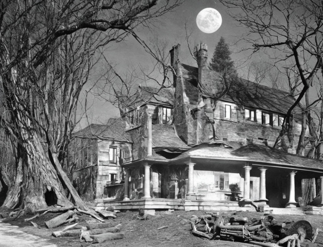 Spooky black and white photo of old house with full moon