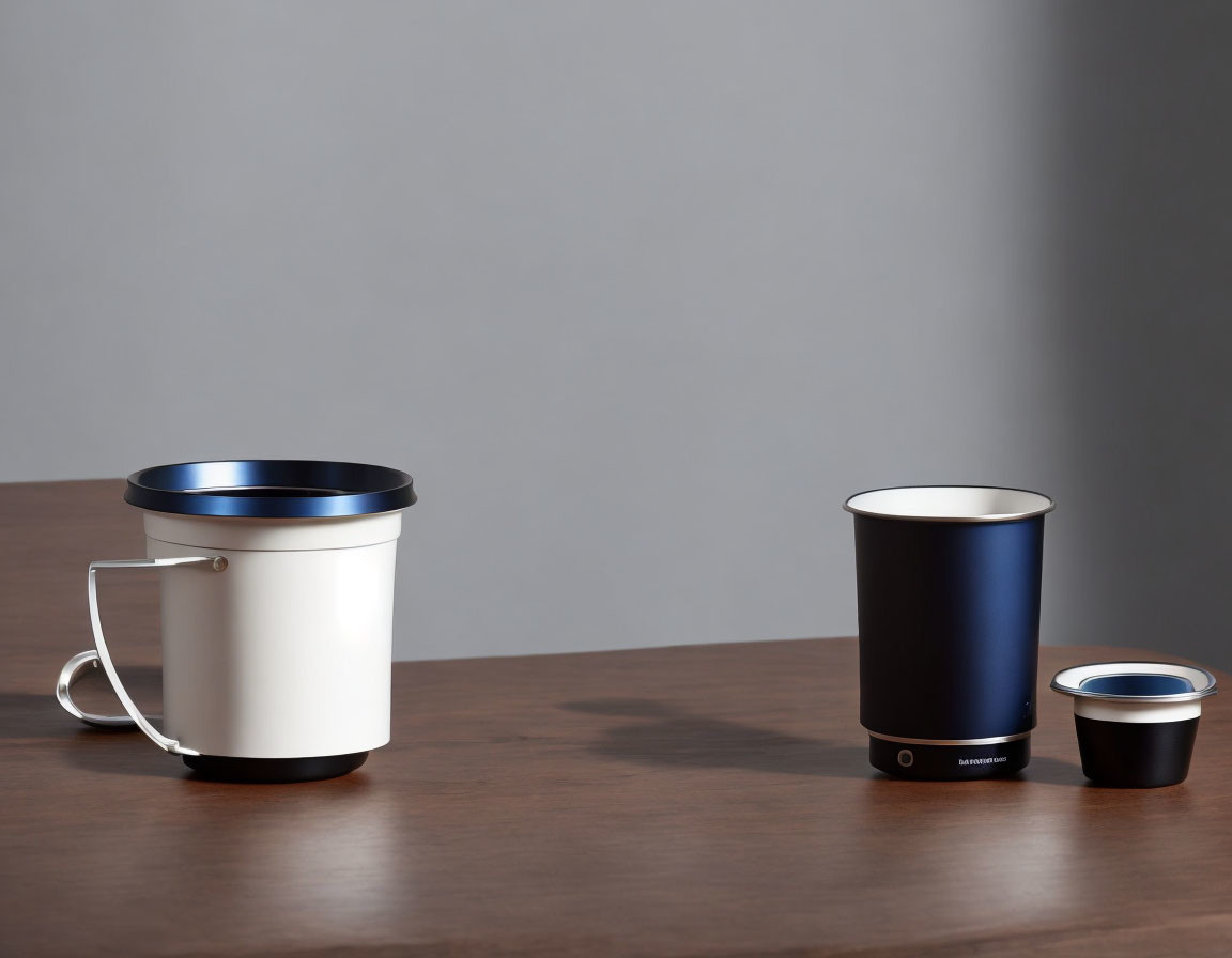 Modern designer cups in white, black, and navy on wooden surface