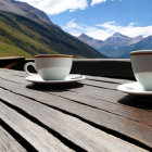 Scenic mountain landscape with two cups of coffee on wooden table