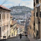 Historic European cobblestone street with traditional houses and distant domed structures