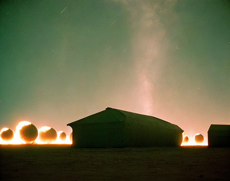 Desert night sky with traditional structures and star trails