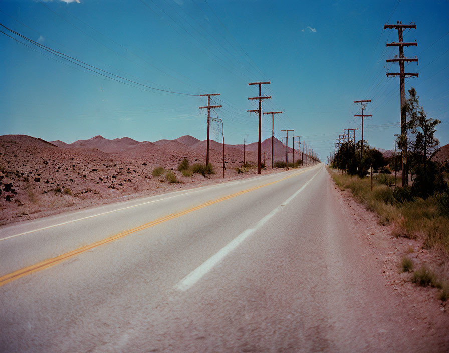 Desert landscape with utility poles on empty road