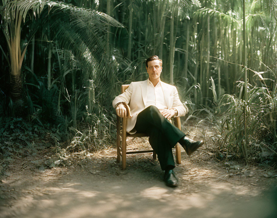 Man in Cream Suit Sitting Among Dense Green Foliage