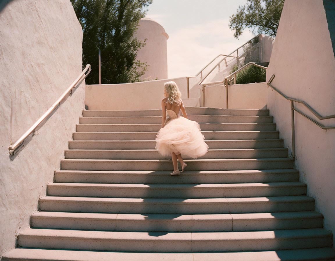 Woman in Peach Dress Climbs Sunlit Outdoor Stairs