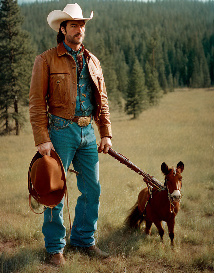 Confident cowboy in leather jacket and hat with horse in field