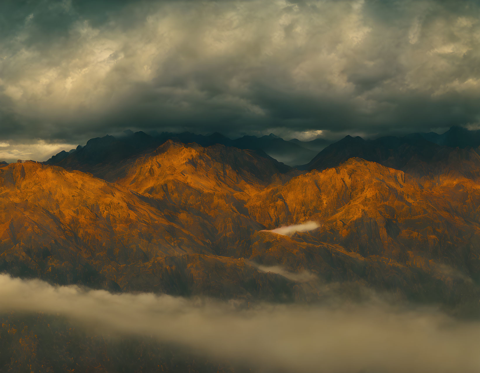 Dramatic sunset over rugged mountains with low clouds and mist.