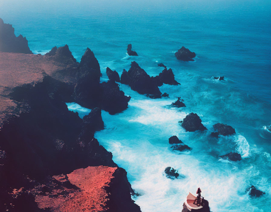 Rugged coastline with cliffs and lighthouse by turbulent ocean waves