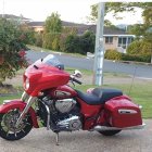 Colorful Red and Black Motorcycle Parked Outdoors with Trees and Concrete Wall