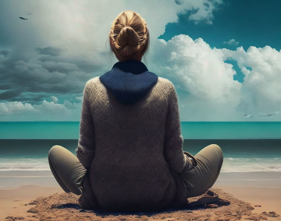 Person with bun hairstyle sitting on beach, gazing at sea and cloudy sky