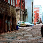 Desolate post-apocalyptic urban street scene with damaged buildings, debris, and fallen autumn leaves.