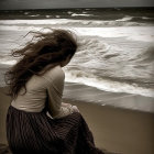 Person sitting on stormy beach with turbulent sea and cresting wave.