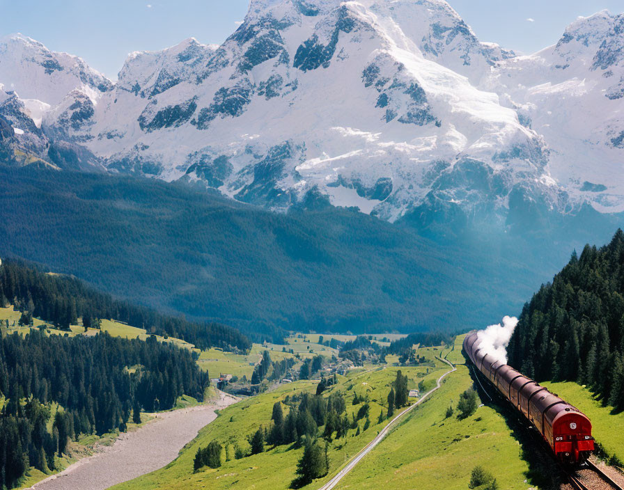 Vintage red train in green valley with snow-capped mountains and blue sky